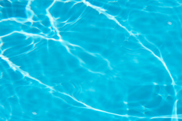 Blue water with ripples on the surface. Defocus blurred transparent blue colored clear calm water surface texture with splashes and bubbles. Water waves with shining pattern texture background.