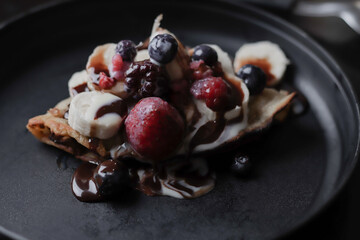 Dark food: rich breakfast, full of vitamins, wheat flour crepes, accompanied by chocolate and dulce de leche and sugar, with tasty red fruits, such as strawberry, raspberry, blueberries.