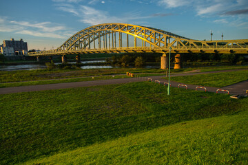 Fototapeta premium Asahibashi bridge cross over the Ishikari river with outdoor park on the riverbank, Asahikawa, Kamikawa Subprefecture, Hokkaido, Japan