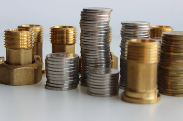 Sanitary And Plumbing Accessories Shop. Fittings And Connection Nuts Near Columns Of Coins Isolated Stock Photo
