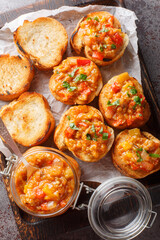 Bread toasts with eggplant caviar closeup on the wooden board on the table. Vertical top view from above