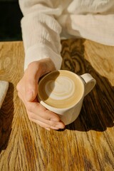 Close-up of a woman's hand with a cup of cappuccino