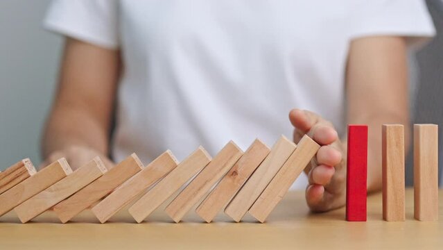 Hand stop falling wood domino blocks on table. Crisis, fall Business, Risk management, Economic recession, Strategy and solutions concept