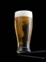 Fresh cold beer in a glass on table on black background.