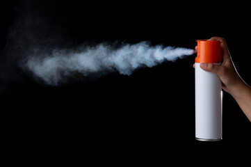 Hand holding a unlabeled white aerosol can with spray in black back