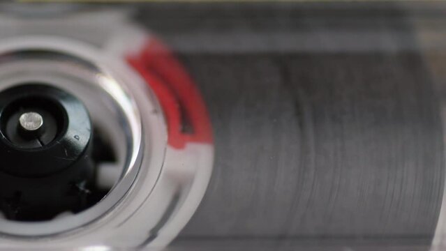 extreme close-up of a reel winding a tape of a vintage audio cassette, a retro audio cassette from the 80s, selective focus. recording music on a cassette recorder