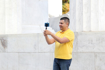 Dark-haired Latino adult man records video on his cell phone broadcasts live on the internet in streaming as an influencer on the street makes recommendations