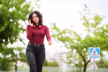 Woman talking on the phone while walking outdoors. Technology concept.