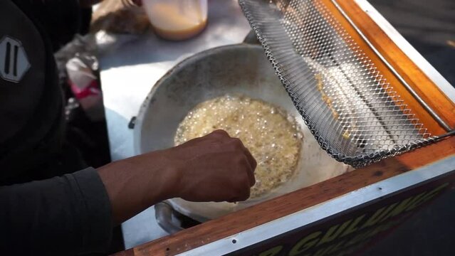 Seller of egg roll snacks (traditional Indonesian snack) pouring batter into a frying pan close-up