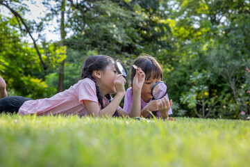 Naklejka na ściany i meble Using a magnifying glass to look at insects in the grass can be an exciting and educational activity for children.