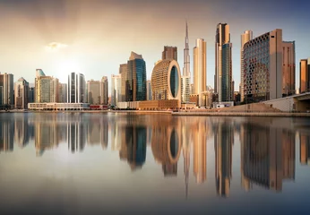 Gordijnen Dubai skyline with reflection at dramatic sunset with sun in United Arab Emirates © TTstudio