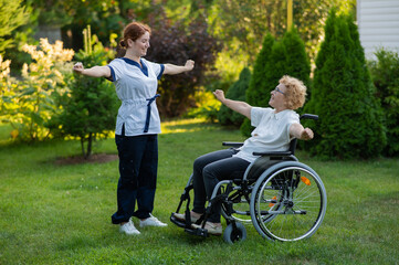 A nurse is exercising with an elderly patient in a wheelchair outdoors.