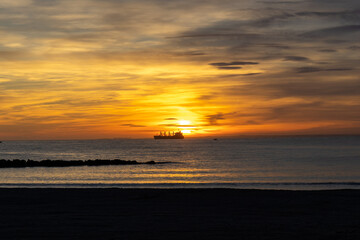 Sunset on the Zapillo beach in Almeria, Spain, ship in front of the Sun