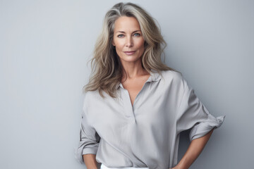 Beautiful middle aged woman leaning against a white wall