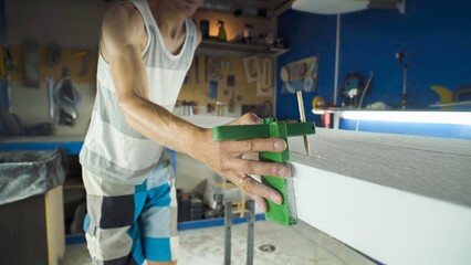Male surfboard shaper making surfboard in his workshop. Hand shaping from blank.