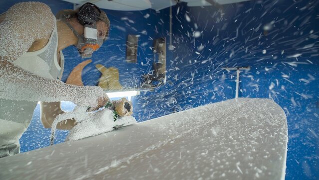 Male surfboard shaper making surfboard in his workshop. Hand shaping from blank.