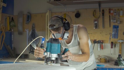 Male surfboard shaper making surfboard in his workshop. Hand shaping from blank.