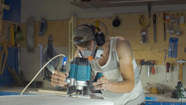 Male surfboard shaper making surfboard in his workshop. Hand shaping from blank.