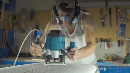 Male surfboard shaper making surfboard in his workshop. Hand shaping from blank.