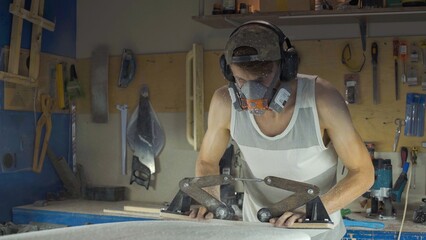 Male surfboard shaper making surfboard in his workshop. Hand shaping from blank.