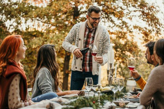 The essence of a memorable garden lunch, the host pouring a wine, and friends come together to create cherished moments in a picturesque outdoor setting.