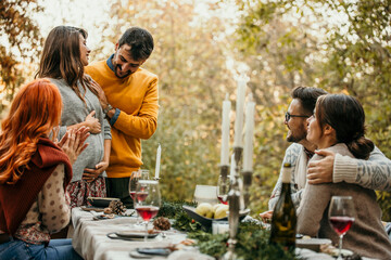 The joyous ambiance of a garden party, with a couple proposal with a diverse group of people relishing a shared meal amidst nature's beauty.
