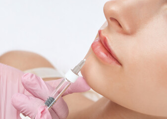Cosmetologist does injections for lips augmentation anti wrinkle injections on the face of a...
