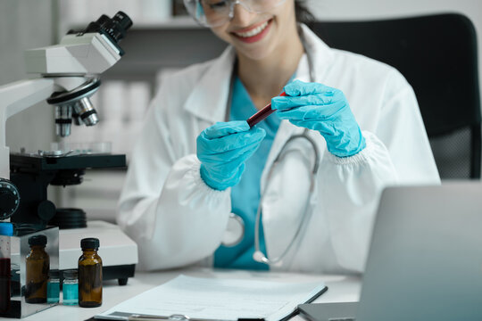 Doctor taking a blood sample tube from a rack with machines of analysis in the lab background, Technician holding blood tube test in the research laboratory.