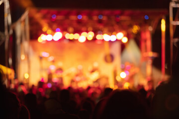 Silhouettes of concert crowd with stage lights, out of focus blurred photo