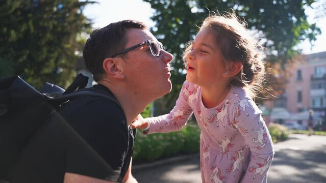 child daughter kissing father in. the cheek outdoors on summer day. Close family relations, modern parenthood concept. quality time with kids