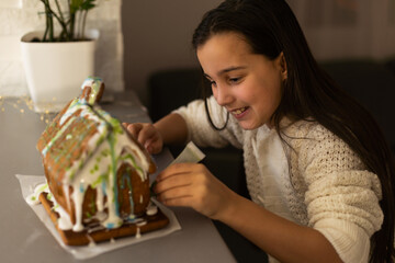 Little girl decorating gingerbread house for Christmas