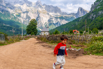 Obraz premium A very happy child running in the valley of Theth national park, Albania. albanian alps