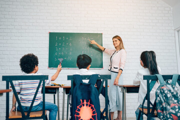 Happy school teacher and students having interesting engaging activities in class. Little children sitting around classroom table, talking and playing fun games together