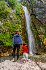 Mother with her son Grunas waterfall of Theth national park in summer, Albania. Albanian alps