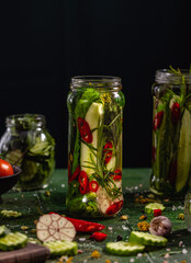 Canned cucumbers with home garden vegetables and herbs. Pickling fresh cucumbers after harvest.