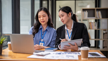 Two beautiful and focused young Asian businesswomen are sharing their project ideas.