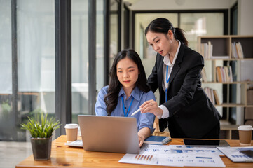 A professional Asian businesswoman or female manager is helping her colleague on a project.