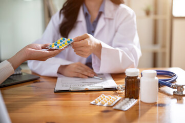 A professional female doctor is describing pills to a female patient during an appointment.