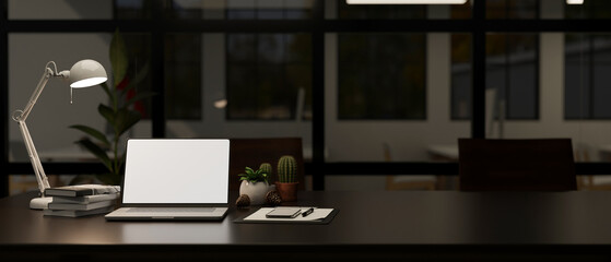 A white screen laptop mockup on a meeting table in a modern meeting room at night.