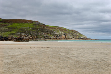 Looking north to the headland on one end of Garry Beach on the Isle of Lewis on an overcast day in June, with the flat empty beach at low tide.