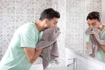 Handsome man washing his face in the bathroom. Morning routine and hygiene concept	