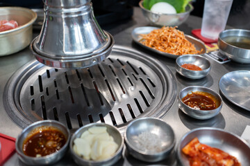 Korean barbecue set of ready for grill with slide beef, pork, soup and traditional Korean vegetables side dish as Kimchi on stainless stove at Korean bbq restaurant. Asian traditional food concept. - 643957652