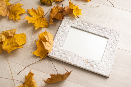 Autumn composition. Photo frame mockup with dried leaves flowers on white background. Autumn, fall, halloween concept. Flat lay, top view, copy space, square