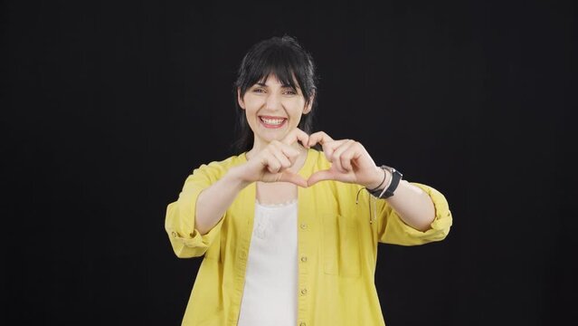 Woman making heart sign at camera.
