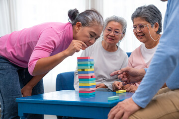 Group of senior people sitting at the table and playing board games together in nursing home