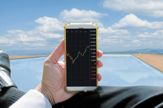 Smart phone monitoring trade curve, that show rise up profit money of marketing share, sunshine vocation swiming relax