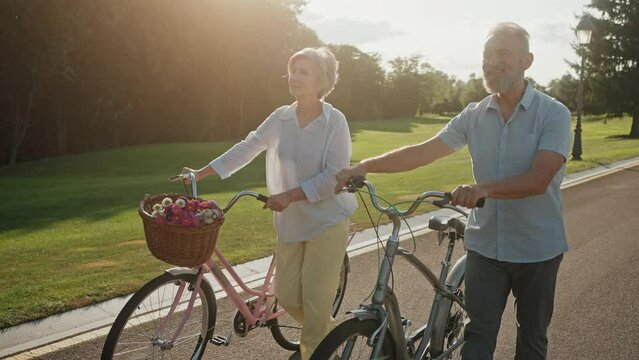 Senior active couple enjoying romantic walk with bicycles