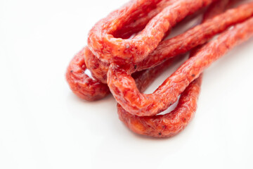 Pork or beef sausage, dry sausages, meat stick smoked close-up. Polish thin, long, dry sausage on a white background