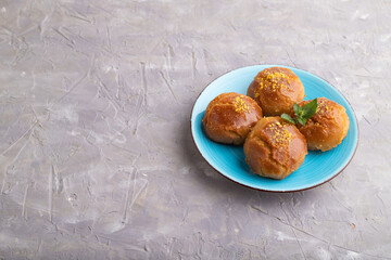 Traditional turkish dessert sekerpare with almonds and honey on gray concrete, side view, copy space.
