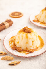 White milk jelly with caramel sauce on gray concrete, side view, selective focus.